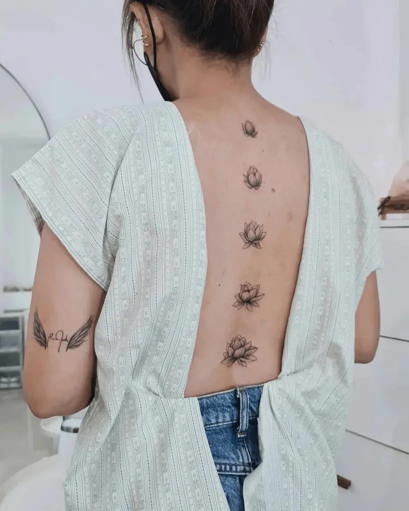 Unique Budding Lotus Flower Tattoos Along Woman’s Spine
